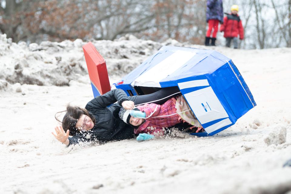 Racers in the sled 'Mighty Pup Cruiser' slide down the route in the Festivus Cardboard Sled Competition at Leila Arboretum on Saturday, Feb. 10, 2024.
