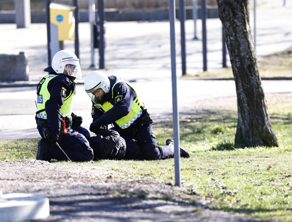 Riot police arrest a person during a riot in Norrkoping, Sweden, Sunday, April 17, 2022. Unrest has broken out in southern Sweden despite police moving a rally by an anti-Islam far-right group, which was planning to burn a Quran among other things, to a new location as a preventive measure. (Stefan Jerrevang/TT News Agency via AP)