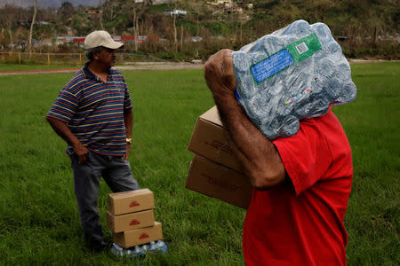 A man carries a case of water away from an HH-60 Blackhawk helicopter after soldiers working with 101st Airborne Division's "Dustoff" unit dropped off relief supplies during recovery efforts following Hurricane Maria, in Jayuya, Puerto Rico, October 5, 2017. REUTERS/Lucas Jackson