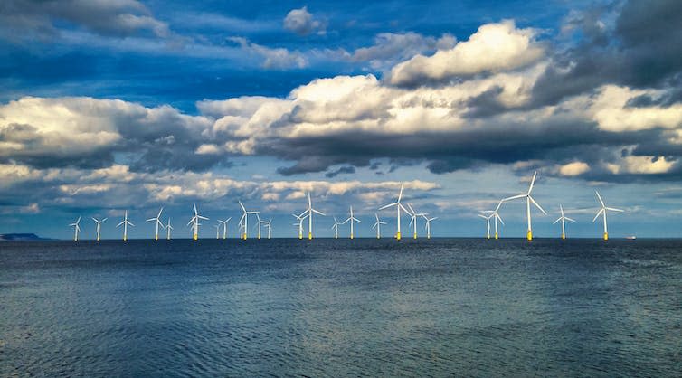 An offshore wind farm under a cloudy sky.