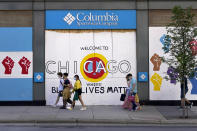 Shoppers walk past Black Lives Matter murals on the boarded up windows and doors of a Columbia clothing store on Chicago's Magnificent Mile on Tuesday, Aug. 11, 2019. (AP Photo/Charles Rex Arbogast)