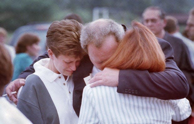 Dennis Dickson of Crescent Township, who lost his wife, Karen, in the crash, hugs his sister, Terri Dickson, left, and sister-in-law Marsha Dickson, after a public memorial service at the Hopewell Township Soccer Field on the one-year anniversary of the crash of Flight 427.