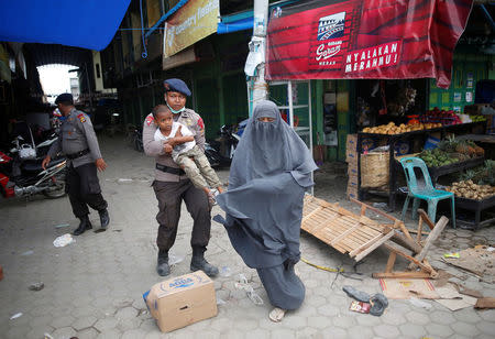 A police officer carries a child as he helps a woman leave a covered market, after an aftershock was felt, following this week's strong earthquake in Meureudu, Pidie Jaya, Aceh province, Indonesia December 9, 2016. REUTERS/Darren Whiteside