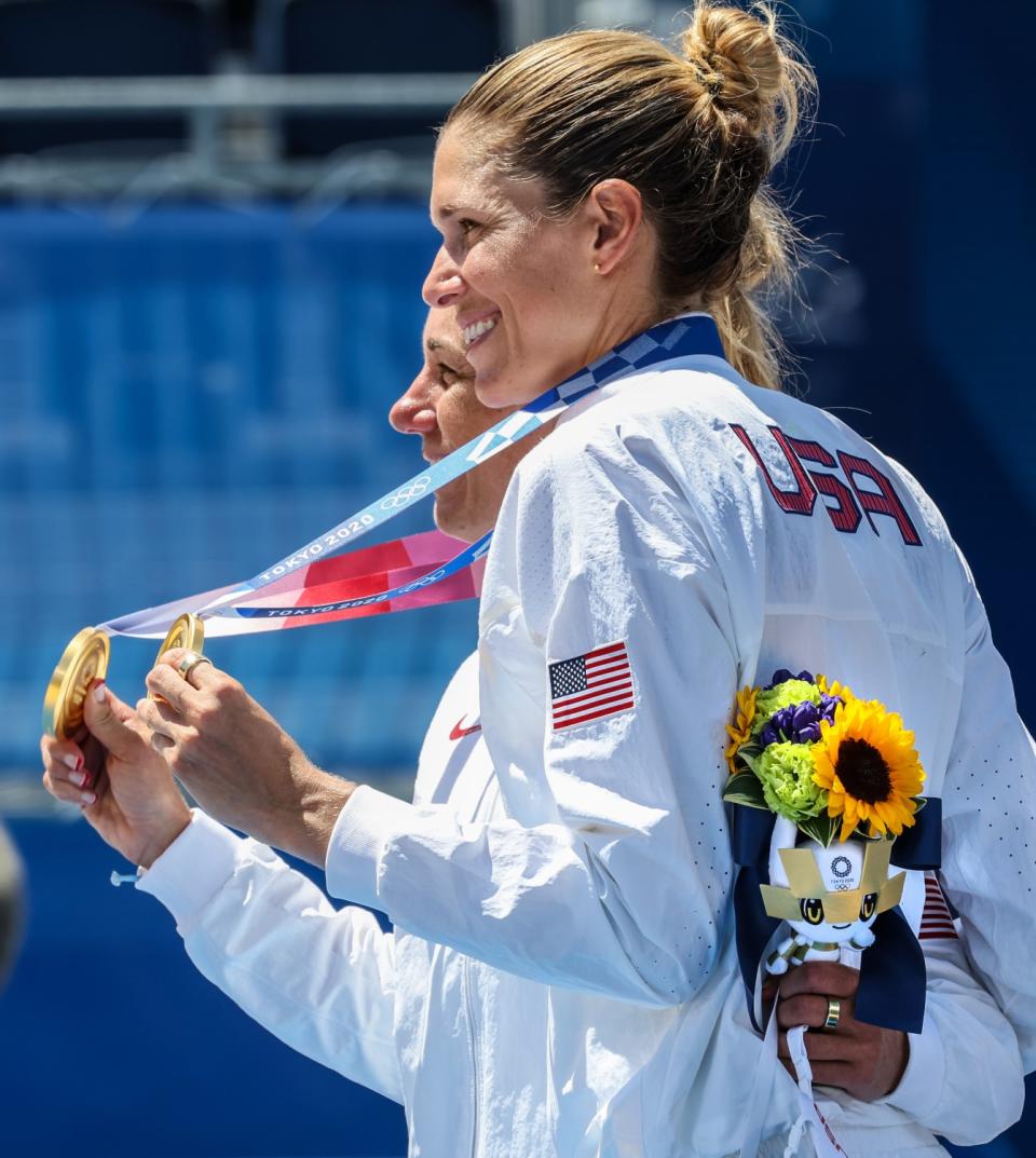 Americans Alix Klineman, right, and April Ross hold up their gold medals after their victory Friday at the Tokyo Olympics.