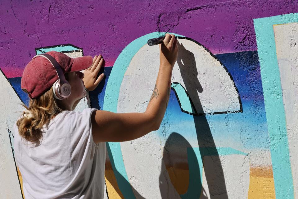 Jessica Picanzo, 22, of Brockton, paints a mural called "Make A Difference" outside Brockton Community Access on Wednesday, July 27, 2022.
