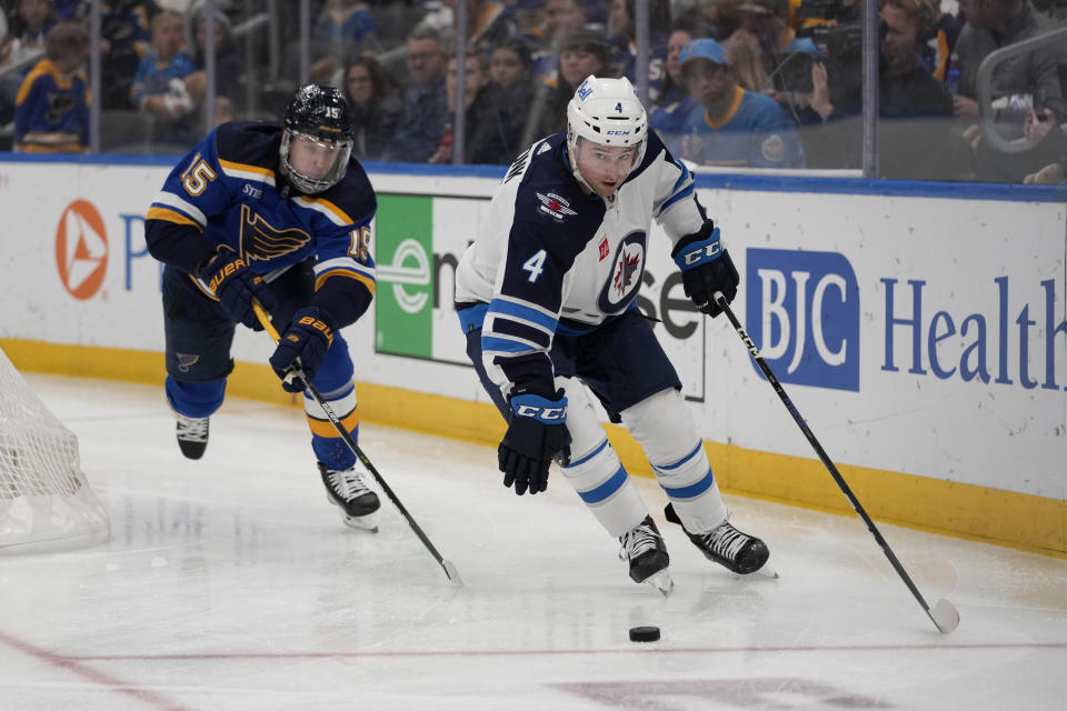 Winnipeg Jets' Neal Pionk (4) controls the puck as St. Louis Blues' Jakub Vrana (15) defends during the second period of an NHL hockey game Sunday, March 19, 2023, in St. Louis. (AP Photo/Jeff Roberson)