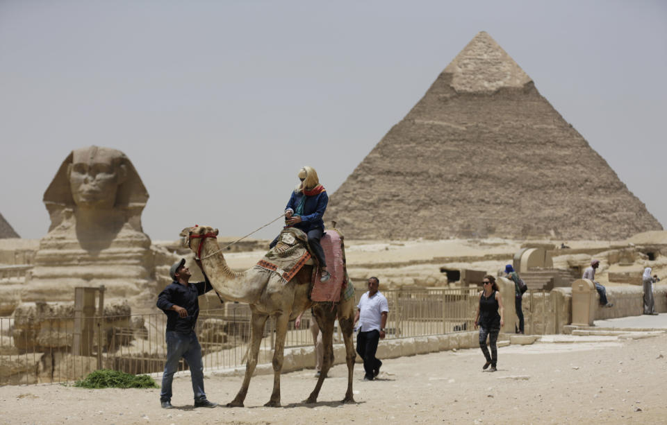 In this photo taken Friday, May 31, 2013, a tourist takes a camel ride at the Giza Pyramids in Giza, Egypt. A statement by Egypt’s Antiquities’ Ministry Saturday, June 1, 2013 says a U.S. Embassy security warning sent to citizens to be extra cautious for their safety in the area of the Pyramids is baseless. Earlier in the week, the U.S. Embassy in Cairo sent a message to its citizens warning them to “elevate their situational awareness when traveling to the Pyramids” due to a “lack of visible security or police” in the area. (AP Photo/Hiro Komae)