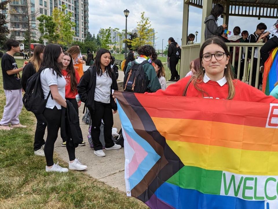 Student Erika Cordeiro holds a Pride flag outside of St. Elizabeth Catholic High School in Vaughan, Ont., where students walked off of school grounds to protest the York Catholic District School Board's decision not to fly the flag.   (Tyler Cheese/CBC - image credit)