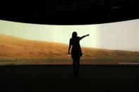 Jacqueline Storey, a press officer at the National Maritime Museum, poses for a photograph in front of images of Mars generated by NASA's Curiosity Rover at their new Visions of the Universe exhibition, in Greenwich, London June 5, 2013. REUTERS/Andrew Winning