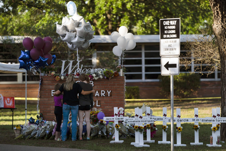 FILE - A family pays their respects next to crosses bearing the names of Tuesday's shooting victims at Robb Elementary School in Uvalde, Texas, Thursday, May 26, 2022. (AP Photo/Jae C. Hong, File)