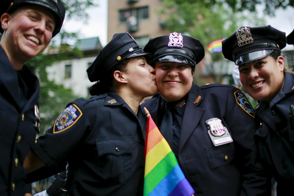 New York Police Department members kiss in front of Stonewall Inn during the annual Gay Pride Parade in New York June 28, 2015. REUTERS/Eduardo Munoz 