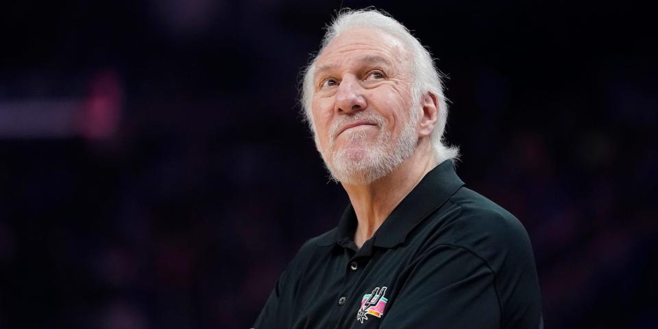 Gregg Popovich folds his arms and looks up during an NBA game.