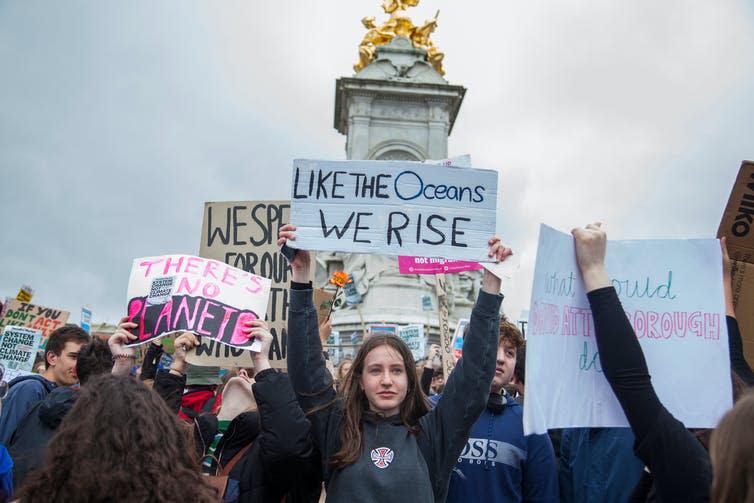 Girl holds up sign in front of monument