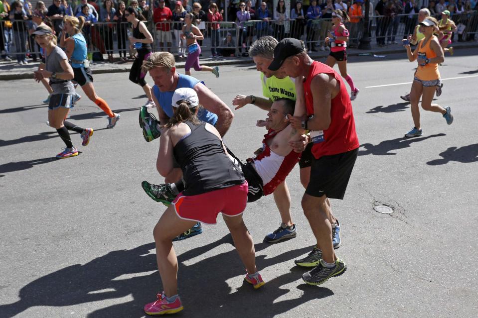 Four runners carry Adam Hurst down Boylston Street after his legs locked up during the 118th running of the Boston Marathon in Boston, Massachusetts in this April 21, 2014 file photo. REUTERS/Dominick Reuter/Files (UNITED STATES - Tags: SPORT ATHLETICS TPX IMAGES OF THE DAY) ATTENTION EDITORS: THIS PICTURE IS PART OF THE PACKAGE 'PICTURES OF THE YEAR 2014 - THE PHOTOGRAPHERS' STORY'. SEARCH 'PHOTOGRAPHERS' STORY' FOR ALL IMAGES'