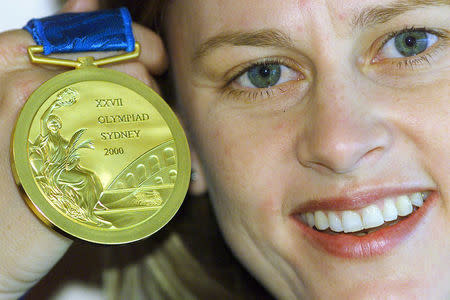 FILE PHOTO - Atlanta hockey gold medallist Danni Roche of Australia holds a display model of a Sydney 2000 Olympic Games gold medal at an unveiling in Sydney, August 12, 2000. REUTERS/Will Burgess/File Photo