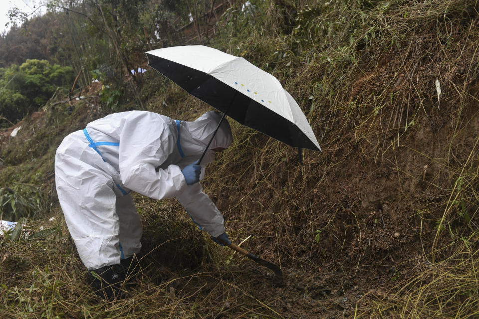 CORRECTS NUMBER OF THE VICTIMS - In this photo released by Xinhua News Agency, a search and rescuer worker wearing a protective suit holds an umbrella using a tool to conduct a search operation at the China Eastern flight crash site in Tengxian County on Saturday, March 26, 2022, in southern China's Guangxi Zhuang Autonomous Region. The second "black box" has been recovered from the crash of a China Eastern Boeing 737-800 that killed 132 people last week, Chinese state media said Sunday. (Lu Boan/Xinhua via AP)