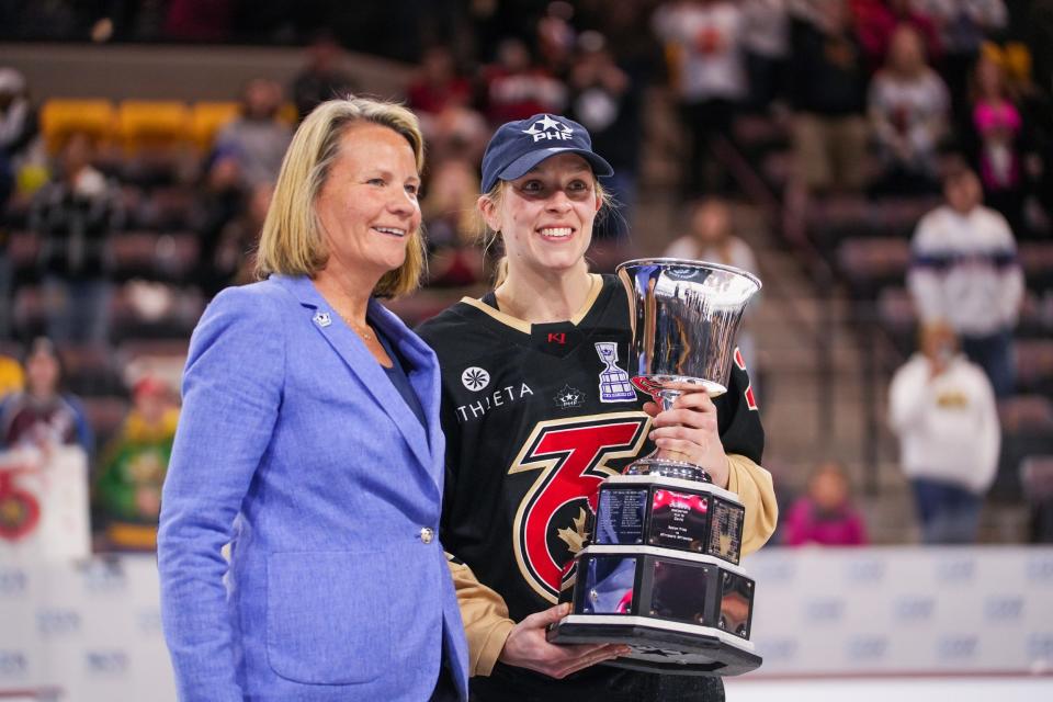 Shiann Darkangelo of Brighton (right) receives the Isobel Cup from Premier Hockey Federation commissioner Reagan Carey as captain of the Toronto Six, which beat the Minnesota Whitecaps in overtime on March 26 in Tempe, Ariz.
