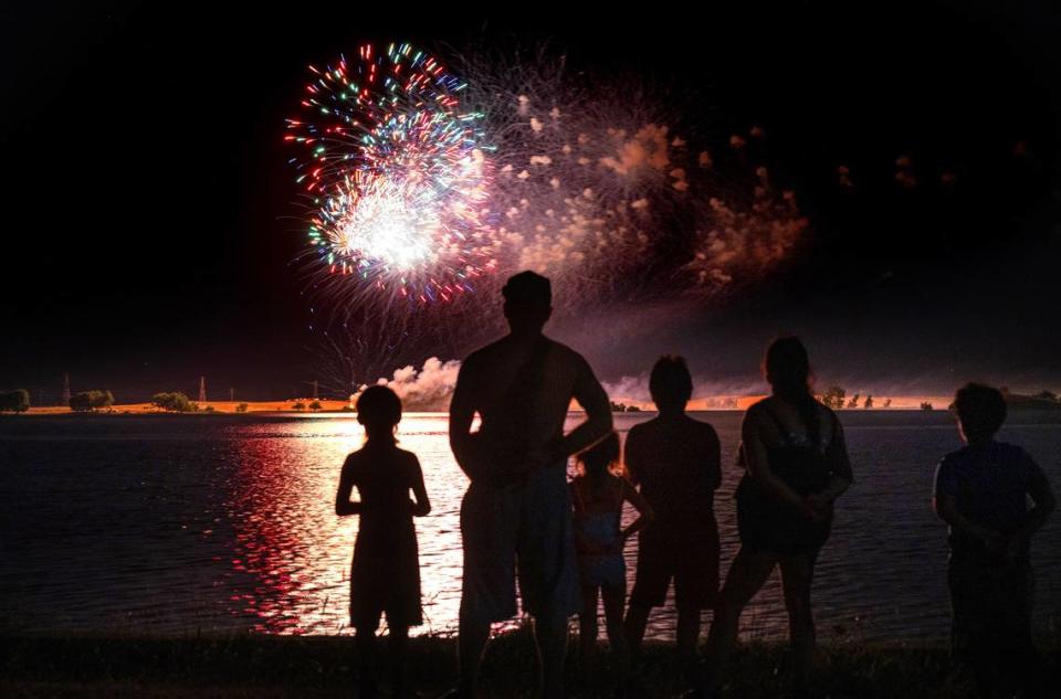 A family watches the Fourth of July fireworks presentation at Woodward Reservoir in Oakdale, Calif., Saturday, July 1, 2023.