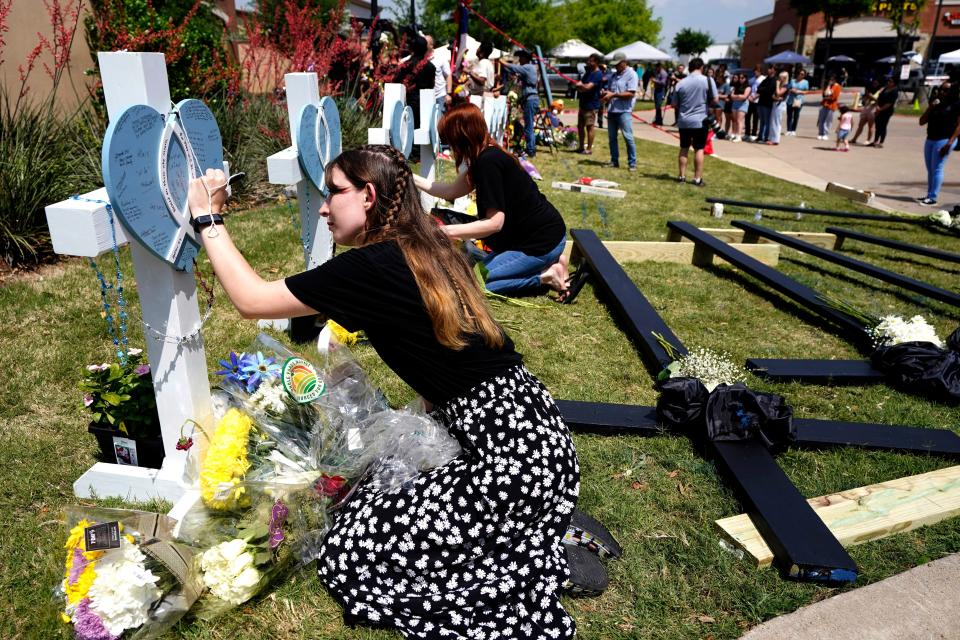 In this May 8, 2023, photo, Jennifer Seeley leaves a message on a cross that has the name of security guard Christian LaCour, written on it at a makeshift memorial in Allen, Texas. (AP Photo/Tony Gutierrez, file)
