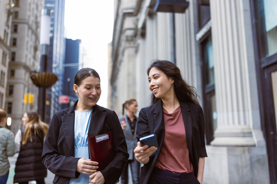 two people walking down the street looking at a phone