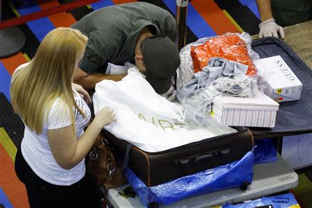 A soldier checks the luggage of a passenger at a security check point at the Simon Bolivar airport in La Guaira, outside Caracas October 15, 2013. REUTERS/Carlos Garcia Rawlins