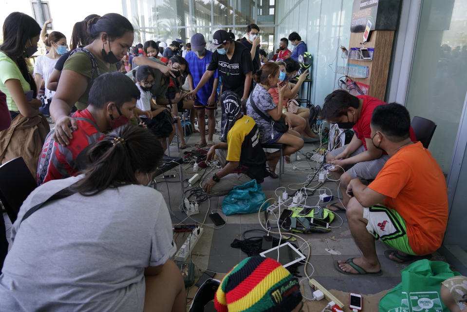 Residents line up to charge their phones for free at a mall after Typhoon Rai damaged power lines and other parts of Cebu city, central Philippines on Saturday, Dec. 18, 2021. A strong typhoon engulfed villages in floods that trapped residents on roofs, toppled trees and knocked out power in southern and central island provinces, where more than 300,000 villagers had fled to safety before the onslaught, officials said. (AP Photo/Jay Labra)