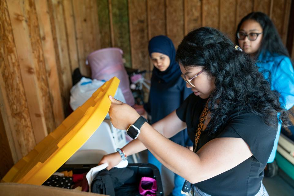 A Girl's Dream founders Miryim Hanek, 21, of Dearborn, left, looks on as Ivett Facundo, 21, goes through a bin of clothes in the garage of Brianna Bryant, 21, of Detroit, Wednesday, Aug. 10, 2022. The trio together started A Girl's Dream with the goal of engaging young women of color in STEAM (Science, Technology, Engineering, Arts and Math) fields. The group has made kits that include a variety of project-oriented activities including paints and chia seeds, etc. Their efforts also include donated clothes to help when girls need to look a little more professional for job interviews or workshops.