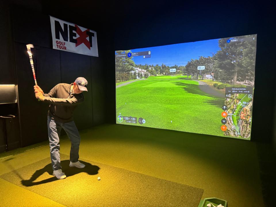Jerre Fillmore takes a swing at one of the virtual golf courses at his business.