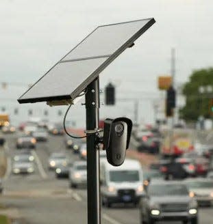 Flock Safety license plate reading cameras are set up to scan all vehicles passing on a road.