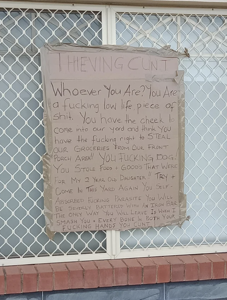 A very long sign calling someone a "lowlife piece of shit" and saying they'll beat them with an iron bar for stealing food meant for their 2-year-old daughter