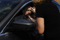 A man drives up in his car to a tent where he receives ashes and prayers from Rev. Kim Robles of the Miami Shores Presbyterian Church on Wednesday, Feb. 26, 2020, in Miami Shores, Fla. Ash Wednesday marks the beginning of Lent, a solemn period of 40 days of prayer and self-denial leading up to Easter. (AP Photo/Brynn Anderson)