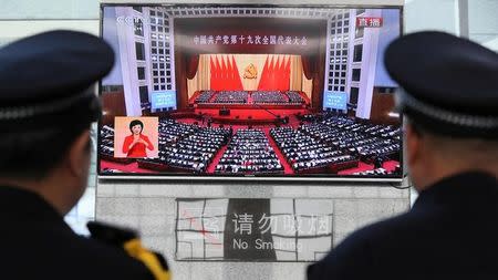 Policemen watch a broadcast of Chinese President Xi Jinping delivering his speech during the opening of the 19th National Congress of the Communist Party of China, as they stand guard at a railway station in Yuncheng, Shanxi province, China October 18, 2017. REUTERS/Stringer