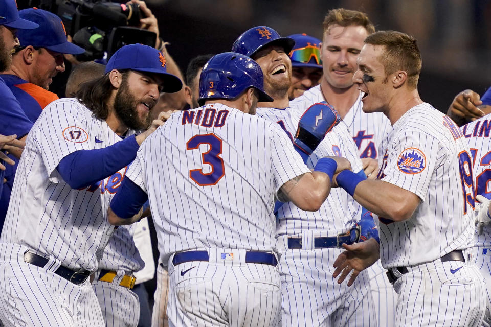 New York Mets catcher Tomas Nido (3) and center fielder Brandon Nimmo, center right, celebrate with their teammates after Nimmo reaches on an infield fielding error to allow the game-winning run by Nido in the tenth inning of a baseball game against the Miami Marlins, Saturday, July 9, 2022, in New York. (AP Photo/John Minchillo)