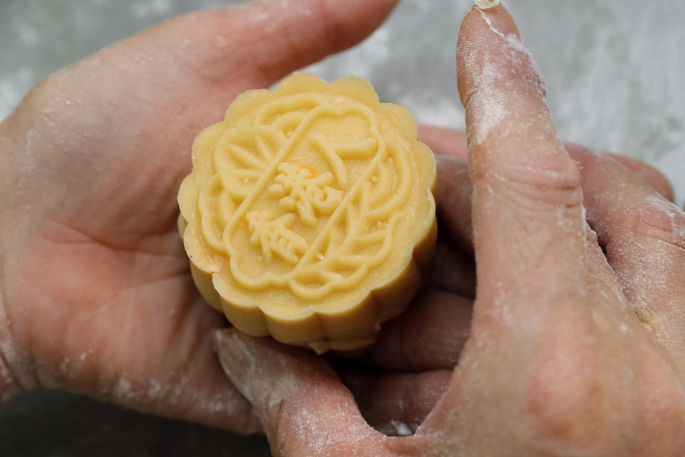 In this Aug. 9, 2019 photo, a staff member makes a mooncake with Chinese words "Hong Kong people" at Wah Yee Tang bakery in Hong Kong. A Hong Kong bakery is doing its part to support the city’s pro-democracy protest movement by making mooncakes with a message. At Wah Yee Tang, the traditional Chinese harvest festival treat comes with a twist: slogans opposing the city’s Beijing-backed government and promoting Hong Kong’s unique identity that have become popular rallying cries since the protests began two months ago.(AP Photo/Kin Cheung)