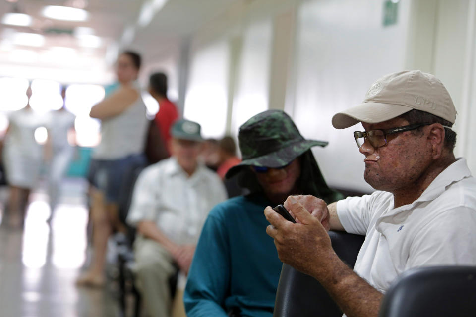 In this April 9, 2014 photo, Deides Freire de Andrade, right, and Djalma Antonio Jardim, behind him, both who have a rare inherited skin disease known as xeroderma pigmentosum, or "XP," wait for medical attention at the Hospital Geral de Goias in Goiania, Goias state, Brazil. More than 20 people in the Araras community of about 800 have XP. That’s an incidence rate of about one in 40 people, far higher than the one in 1 million people in the United States who have it. (AP Photo/Eraldo Peres)