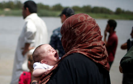 A displaced Iraqi baby cries as its family waits to cross the Tigris River by a boat after the bridge has been temporarily closed, in western Mosul, Iraq May 6, 2017. REUTERS/Suhaib Salem