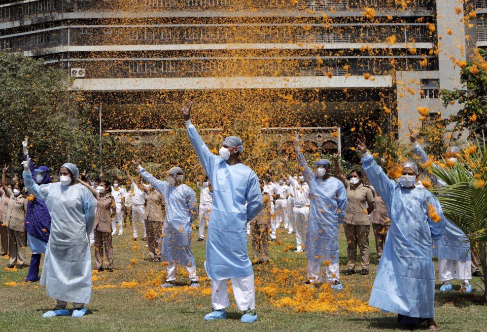 An Indian Air Force helicopter showers flower petals on the staff of INS Asvini hospital in Mumbai, India, Sunday, May 3, 2020. The event was part the Armed Forces' efforts to thank the workers, including doctors, nurses and police personnel, who have been at the forefront of the country's battle against the COVID-19 pandemic. (AP Photo/Rajanish Kakade)