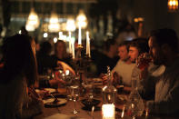 A group of diners have a drink and candle lit dinner at Brasserie Surrealiste in Brussels, Wednesday, Sept. 28, 2022. A group of restaurant owners in Brussels has imagined how a future without gas and electricity would look like for gourmets. Dinner guests, served at the Brasserie Surrealiste and cooked by Racines restaurant employees, were the first to experience it: No ovens, no stoves, no hot plates, no coffee machines and no light bulbs. (AP Photo/Olivier Matthys)