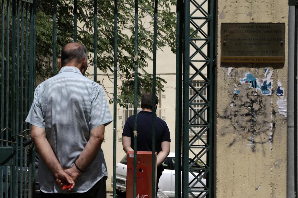 People stand at the entrance of a morgue in Athens, Thursday, July 26, 2018. Relatives searching for loved ones missing in Greece's deadliest forest fire in decades headed to Athens' morgue Thursday, as rescue crews and volunteers continued searches on land and at sea for potential further victims. (AP Photo/Thanassis Stavrakis)