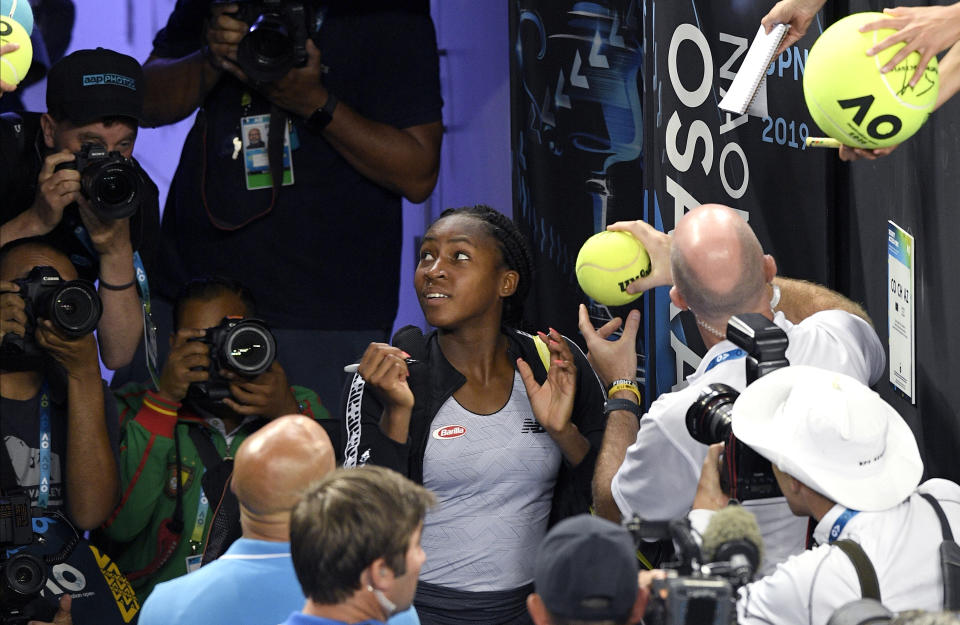 United States' Cori "Coco" Gauff signs autographs after defeating compatriot Venus Williams during their first round singles match at the Australian Open tennis championship in Melbourne, Australia, Monday, Jan. 20, 2020. (AP Photo/Andy Brownbill)