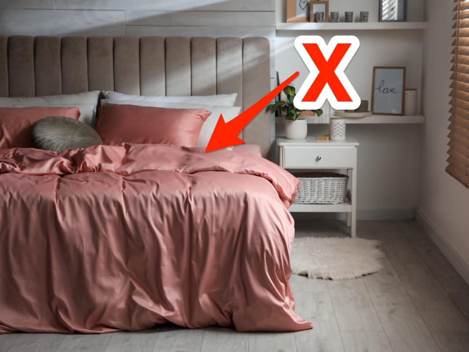 red x and arrow pointing at pink silk bed linens in a modern room