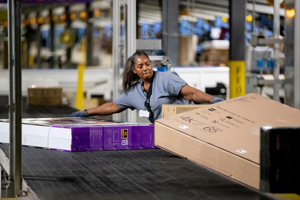 Sharon Short moves large packages onto a conveyor belt Wednesday, Dec. 4, 2019, at the FedEx Ground Olive Branch hub.