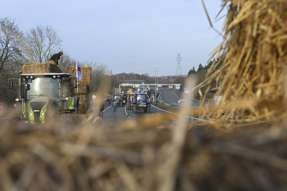 Farmers block a highway near Paris's main airport with hay bales, Monday, Jan. 29, 2024 near Roissy-en-France, north of Paris. Protesting farmers vowed to encircle Paris with tractor barricades and drive-slows on Monday, aiming to lay siege to France's seat of power in a battle with the government over the future of their industry, which has been shaken by repercussions of the Ukraine war. (AP Photo/Matthieu Mirville)