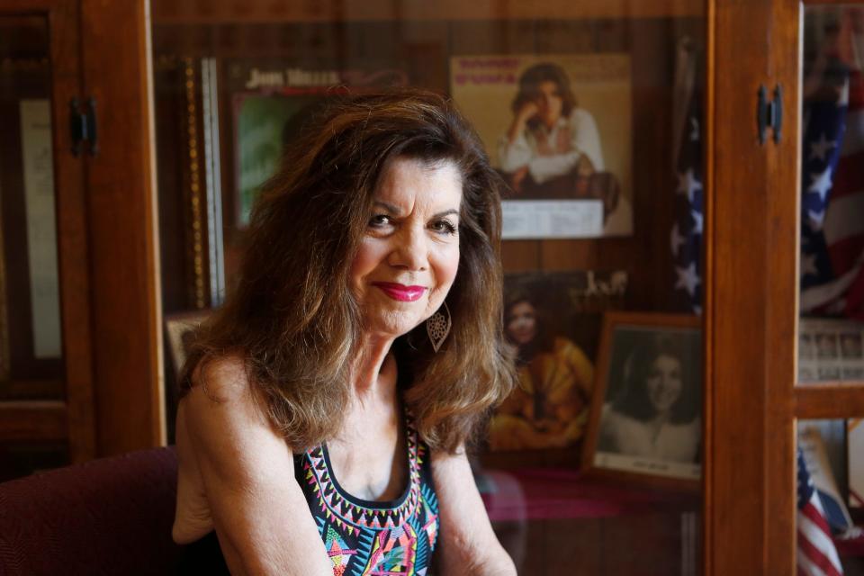 Jody Miller sits in front of a wall with memorabilia from her singing career in the entryway of her old high school in Blanchard, Oklahoma, on June 28, 2018.