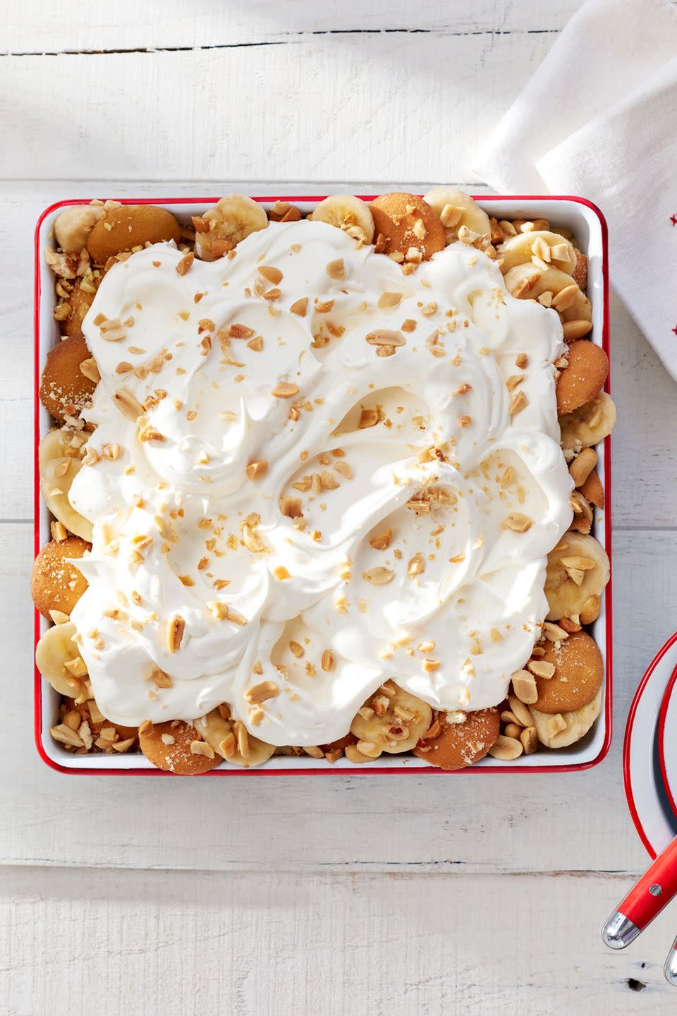 salty peanut banana pudding in a square baking dish and topped with whipped cream and chopped peanuts