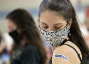 Kent State University student Regan Raeth of Hudson, Ohio, looks at her vaccination bandage as she waits for 15 minutes after her shot in Kent, Ohio, Thursday, April 8, 2021. U.S. colleges hoping for a return to normalcy next fall are weighing how far they should go in urging students to get the COVID-19 vaccine, including whether they should — or legally can — require it. (AP Photo/Phil Long)