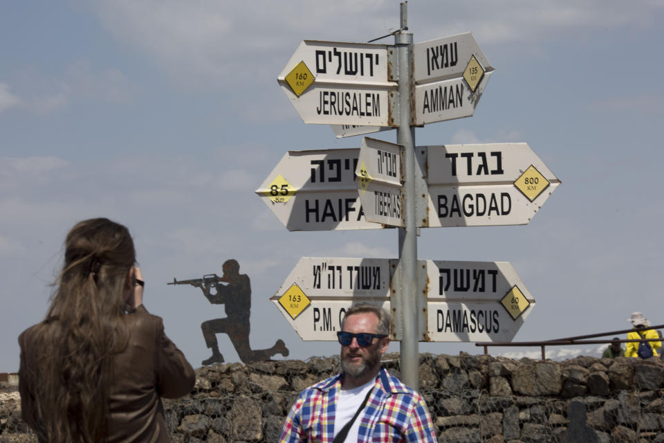 Tourists pose for photograph next to a mock road sign for Damascus, the capital of Syria, and other capitals and cities and a cutout of a soldier, in an old outpost in the Israeli controlled Golan Heights near the border with Syria, Friday, March 22, 2019. President Donald Trump abruptly declared Thursday the U.S. will recognize Israel's sovereignty over the disputed Golan Heights, a major shift in American policy that gives Israeli Prime Minister Benjamin Netanyahu a political boost a month before what is expected to be a close election.(AP Photo/Ariel Schalit)