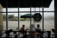 Krystina Francois, left, and Francesca Menes, children of Haitian immigrants to the U.S. and co-founders of the Black Collective, are seen through windows streaked from a recent rain, as they work together outside a Starbucks, Tuesday, Sept. 21, 2021, in Miami Shores, Fla. Menes and Francois, whose advocacy organization focuses on the political needs and economic empowerment of Black people across the African diaspora, have called for the Biden administration to immediately suspend plans to remove migrants via planes bound for Haiti. (AP Photo/Rebecca Blackwell)