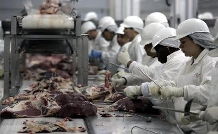 Trabajadores cortan la carne en una de las plantas de JBS, en Sao Paulo, Brasil. 9 de septiembre 2005. La Policía Federal de Brasil lanzó el viernes masivas redadas y allanamientos como parte de una investigación a firmas procesadoras de alimentos acusadas de sobornar a reguladores para que relajen sus controles. REUTERS/Paulo Whitaker/Files (BRAZIL) - RTXBZX4