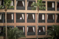 People stand at their balconies at the H10 Costa Adeje Palace hotel in Tenerife, Canary Island, Spain, Tuesday, Feb. 25, 2020. Spanish officials say a tourist hotel on the Canary Islands has been placed in quarantine after an Italian doctor staying there tested positive for the new coronavirus. (AP Photo)